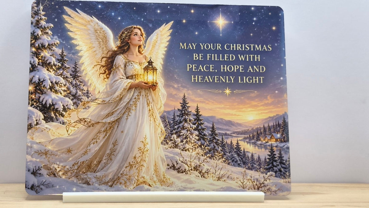 Christmas angel holding a lantern in a snowy landscape with peace, hope and heavenly light wording