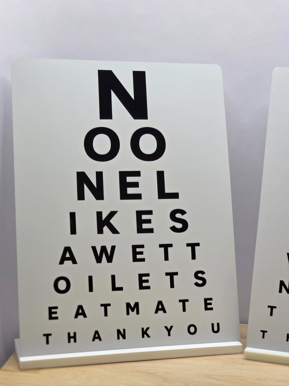 Portrait bathroom metal sign in an eye-test layout with black letters spelling No one likes a wet toilet seat mate thank you
