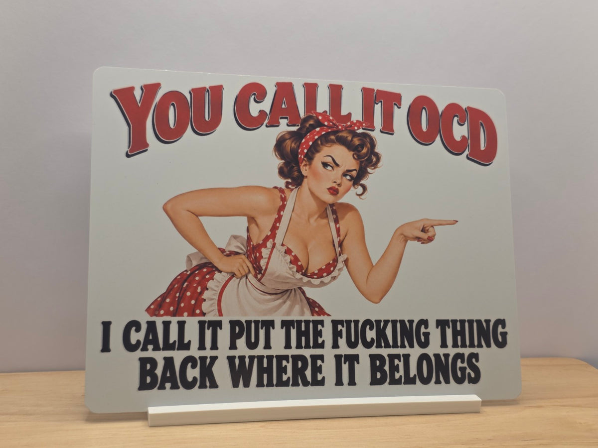 You Call It OCD humorous metal sign with a pointing retro woman and bold red and black wording, displayed in a white stand