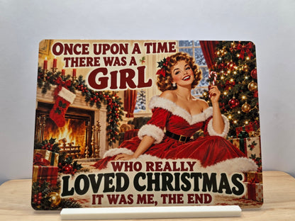 Once Upon a Time Girl Who Loved Christmas metal sign with a woman in a red dress beside a festive fireplace and tree, displayed with stand.
