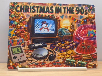 Christmas in the 90s metal sign with retro television, handheld game, CD player, chocolates and festive decorations in a white stand