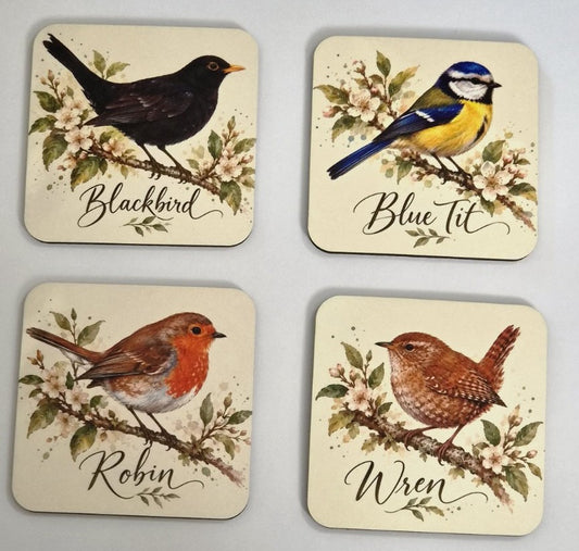 Set of four British garden bird coasters featuring a blackbird, blue tit, robin and wren on blossom branches
