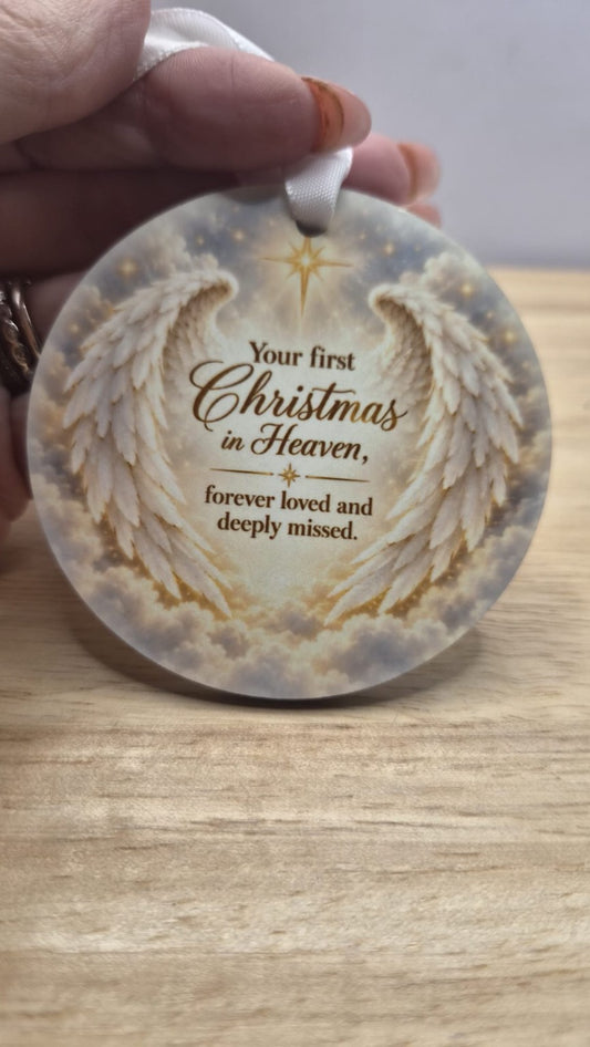 Round memorial tree decoration with white ribbon, angel wings and the words Your first Christmas in Heaven, forever loved and deeply missed