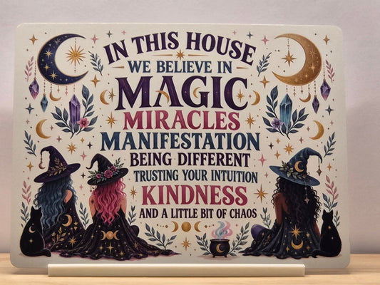 In This House We Believe in Magic metal sign with four witch cats, celestial motifs and colourful wording, displayed in a white stand