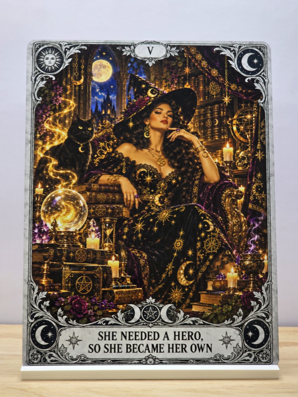 She Became Her Own Hero metal sign with a seated witch, black cat and ornate gold magical artwork, displayed in a white stand