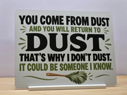 That's Why I Don't Dust funny metal sign with bold black lettering, green leaves and a feather duster, displayed in a white stand