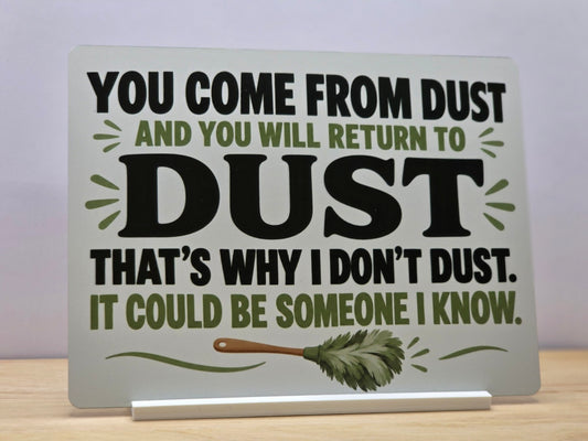 That's Why I Don't Dust funny metal sign with bold black lettering, green leaves and a feather duster, displayed in a white stand