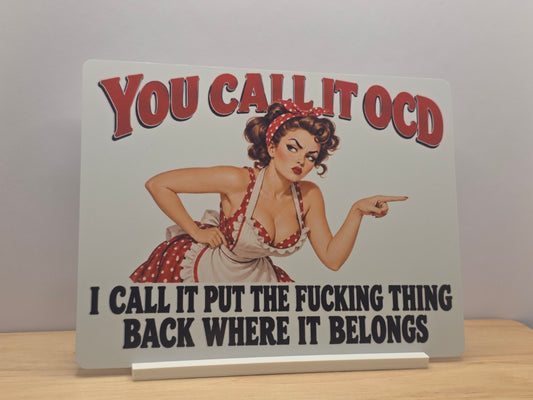 You Call It OCD humorous metal sign with a pointing retro woman and bold red and black wording, displayed in a white stand